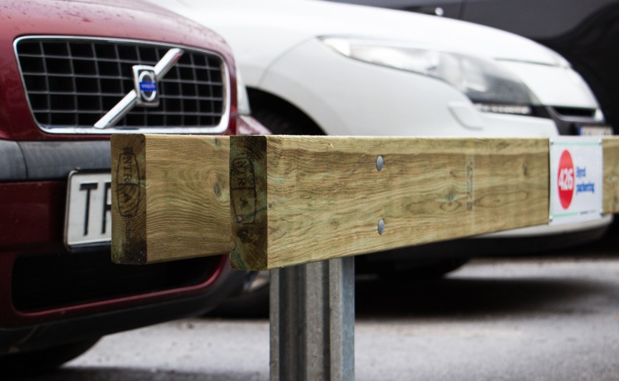 Parkeringsräcke som separerar bilar på parkeringsplats.