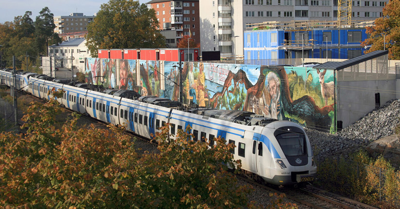 Pendeltåg passerar muralmålningen i Trångsund