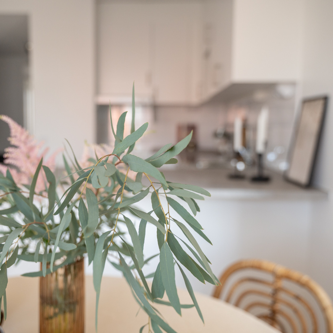 Ett bord med en vas med blommor och ett stearinljus på.