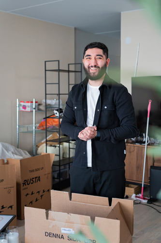 Reza Majidi omgiven av flyttkartonger i sin lägenhet.