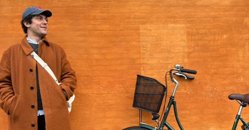 Kemal Akoglu mot orange fasad bredvid cykel